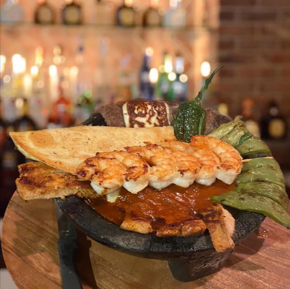 Molcajete with grilled shrimp skewer, nopales and queso at the Los Agaves bar